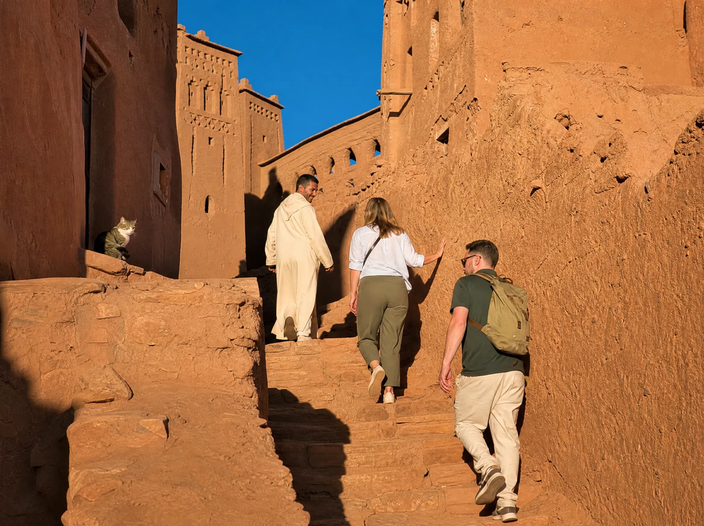 Un guide du village mène deux voyageurs dans les ruelles en terre du ksar d’Aït Ben Haddou, en fin d’après-midi